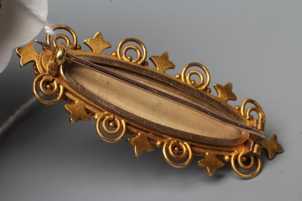 A VICTORIAN MOURNING BROOCH, the eliptical black panel centred by a gypsy set and seed pearl star, Image