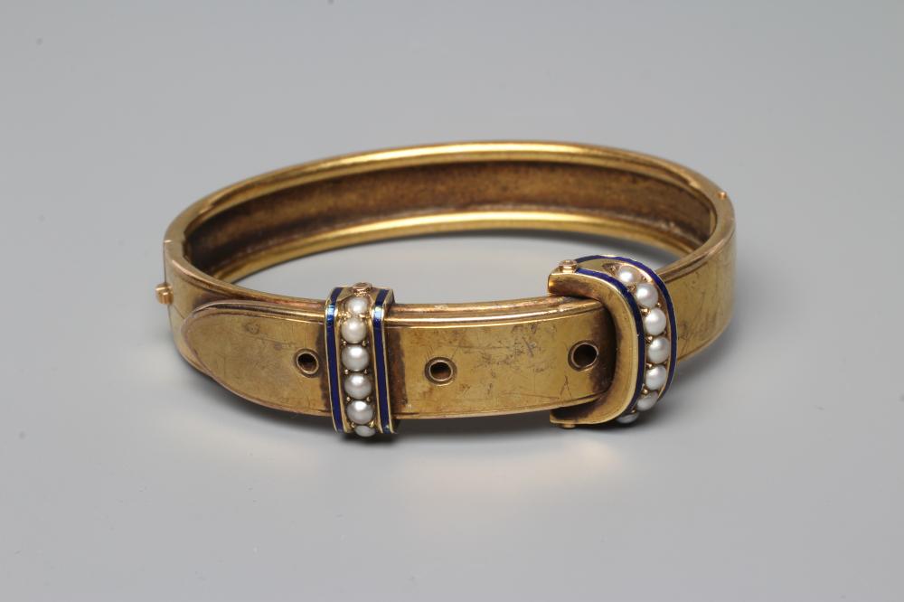 A VICTORIAN STIFF HINGED BUCKLE BANGLE, the upper section with two seed pearl and blue enamel Image