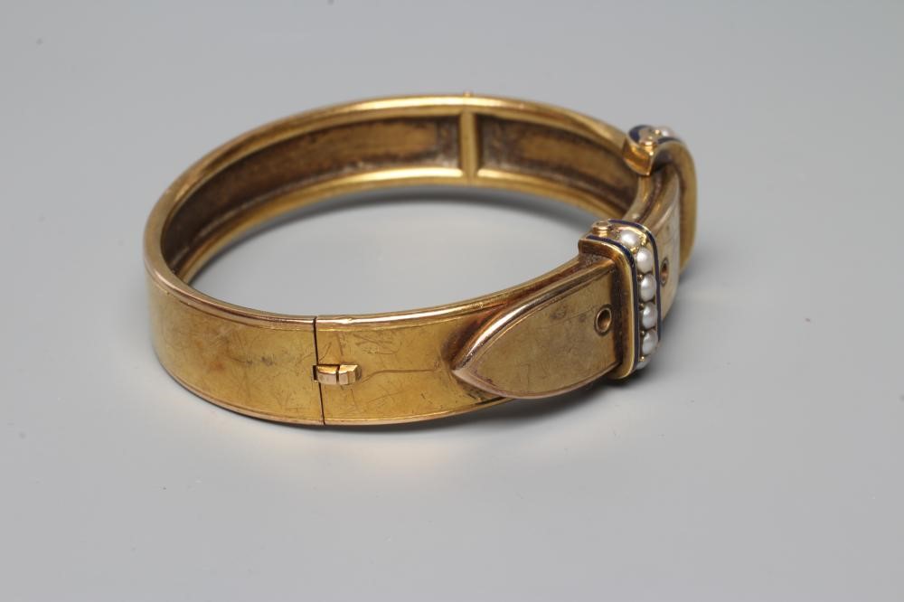 A VICTORIAN STIFF HINGED BUCKLE BANGLE, the upper section with two seed pearl and blue enamel Image