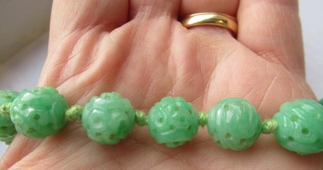 A CHINESE JADE NECKLACE, the twenty nine spherical beads carved and pierced with scrolling foliage, Image