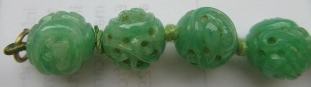 A CHINESE JADE NECKLACE, the twenty nine spherical beads carved and pierced with scrolling foliage, Image