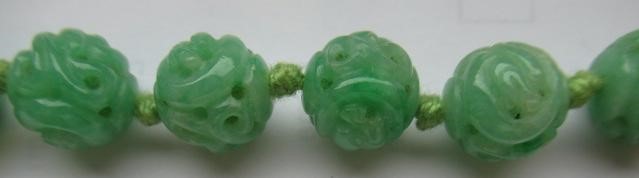 A CHINESE JADE NECKLACE, the twenty nine spherical beads carved and pierced with scrolling foliage, Image