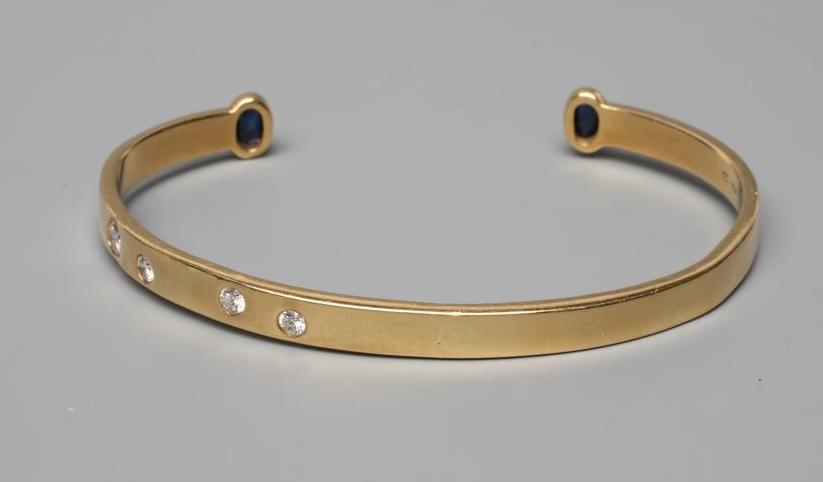 A BANGLE, stamped 750, asymetrically set with four graduated round brilliant cut stones, each Image