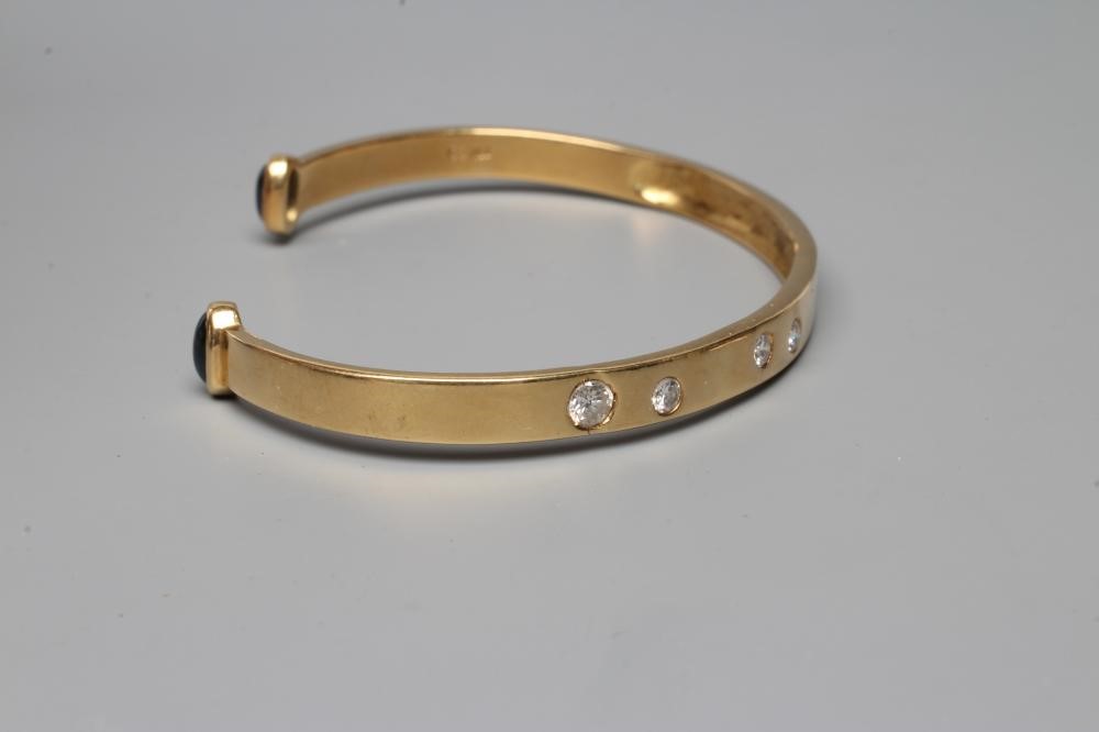 A BANGLE, stamped 750, asymetrically set with four graduated round brilliant cut stones, each Image