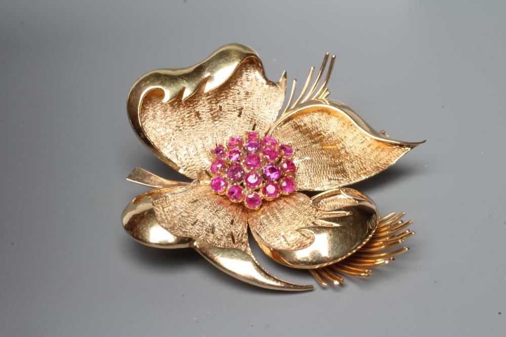A COCKTAIL BROOCH, the large four petalled flowerhead with numerous small rubies claw set to the Image