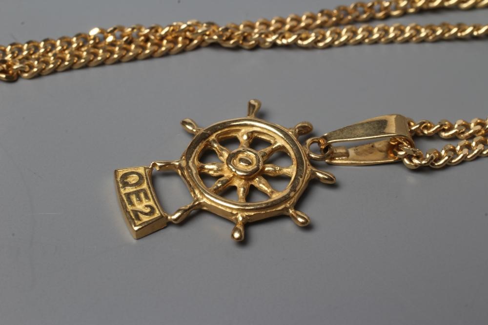 A SOUVENIR PENDANT cast as a ship's wheel and titled "QE2", stamped 18k, on an 18ct gold flat link Image