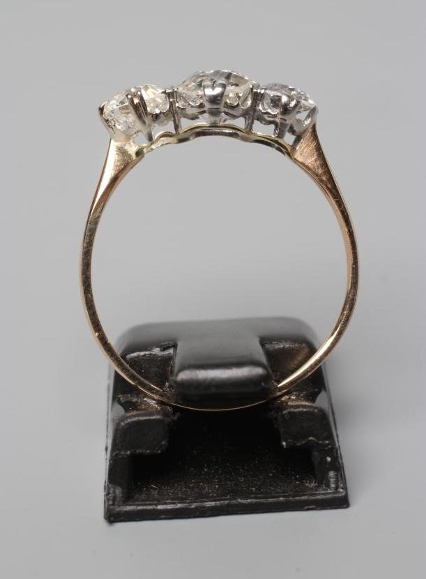 A THREE STONE DIAMOND RING, the old cut stones totalling approximately 1ct, claw set to a plain Image