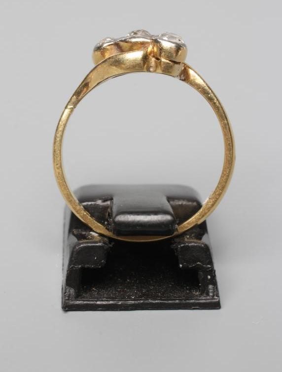 A THREE STONE DIAMOND CROSSOVER RING, the brilliants in rub-over settings to a plain shank stamped Image