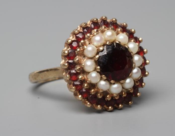 A GARNET AND SEED PEARL CLUSTER RING, point and claw set to a plain shank stamped 9ct, size R (Est. Image