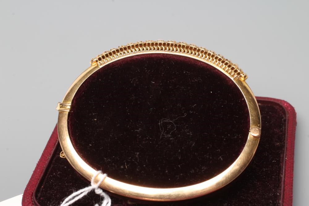 AN EDWARDIAN STIFF HINGED BANGLE, the upper section with nineteen graduated pearls to a plain, Image