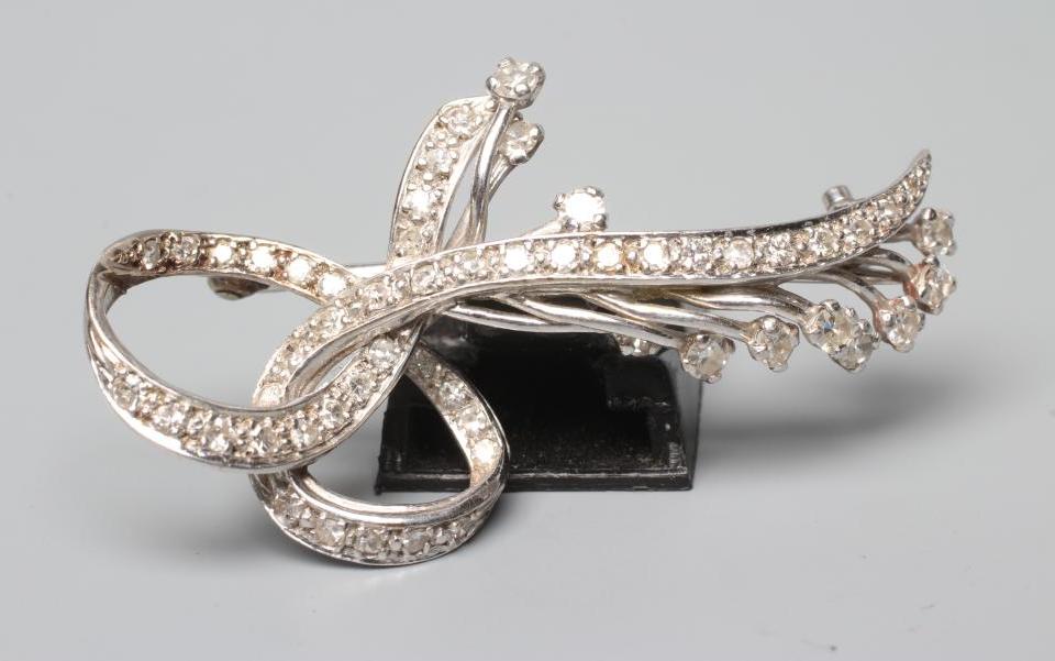 A DIAMOND FLOWER SPRAY BROOCH, with point set scrolling "leaves" to a plain unmarked white frame Image