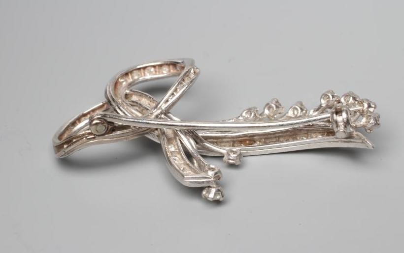 A DIAMOND FLOWER SPRAY BROOCH, with point set scrolling "leaves" to a plain unmarked white frame Image