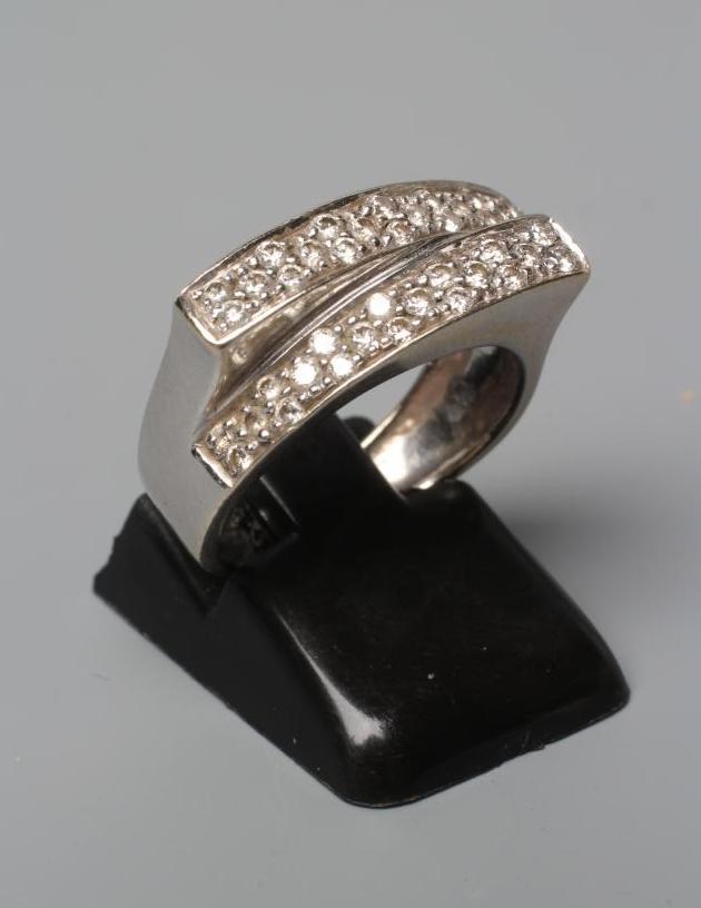 A DIAMOND CROSSOVER STYLE RING, the two panels point set with numerous small stones to a wide white Image