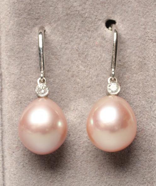 A PAIR OF CULTURED PEARL DROP EARRINGS, the peg set pink tinted tear shaped pearls with collet set Image
