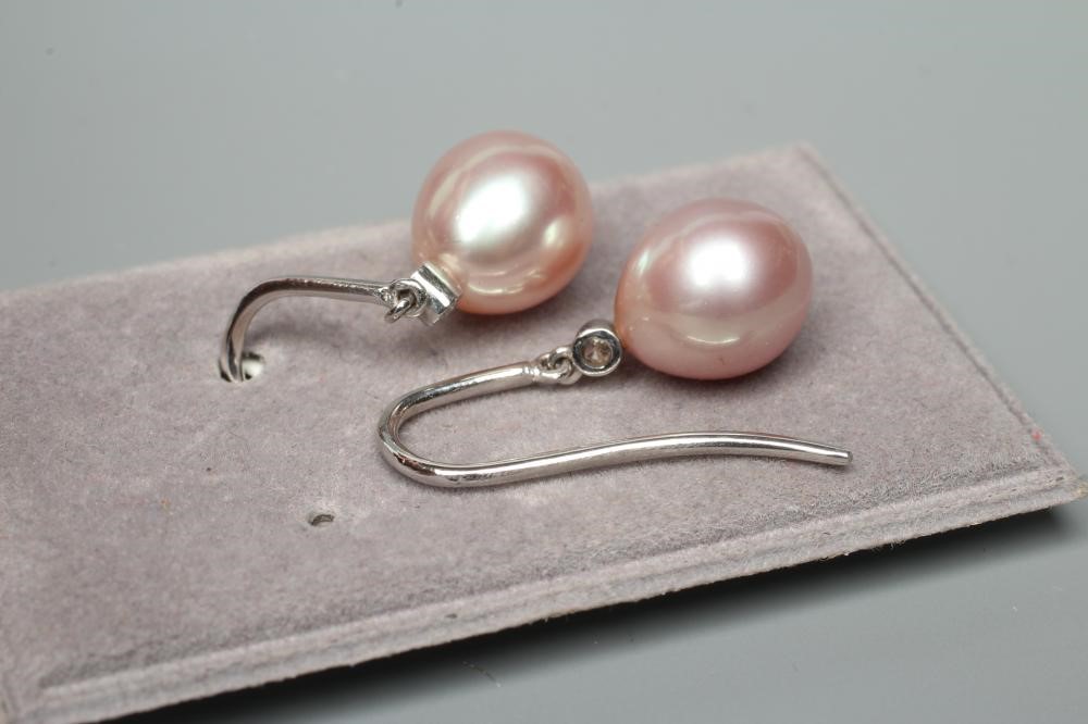 A PAIR OF CULTURED PEARL DROP EARRINGS, the peg set pink tinted tear shaped pearls with collet set Image