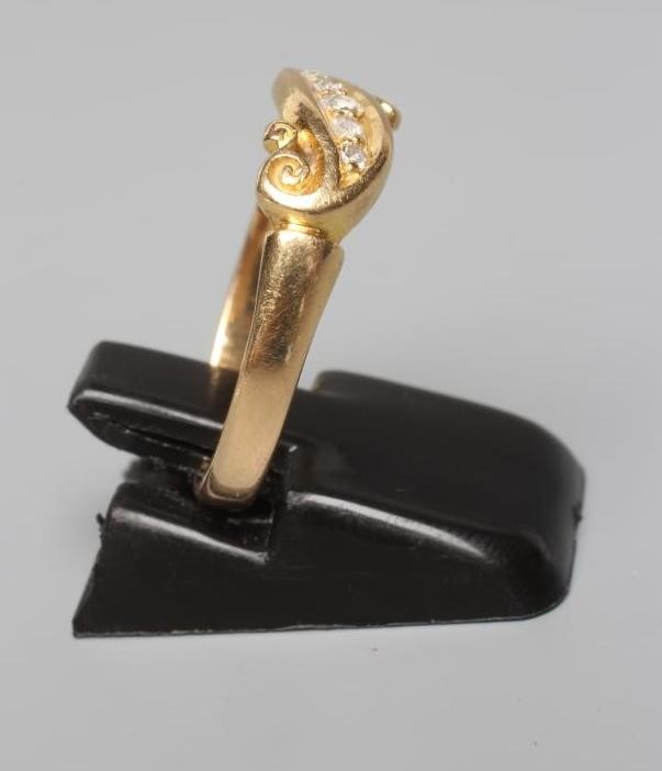 A VICTORIAN FIVE STONE DIAMOND CROSSOVER RING, the small stones point set to scroll carved shoulders Image