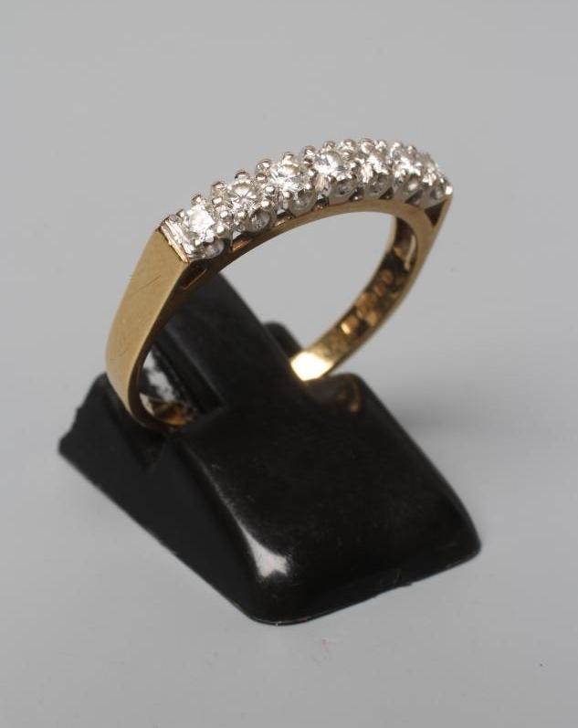 A SEVEN STONE DIAMOND HALF HOOP ETERNITY RING, the brilliant cut stones point set to a plain 18ct Image