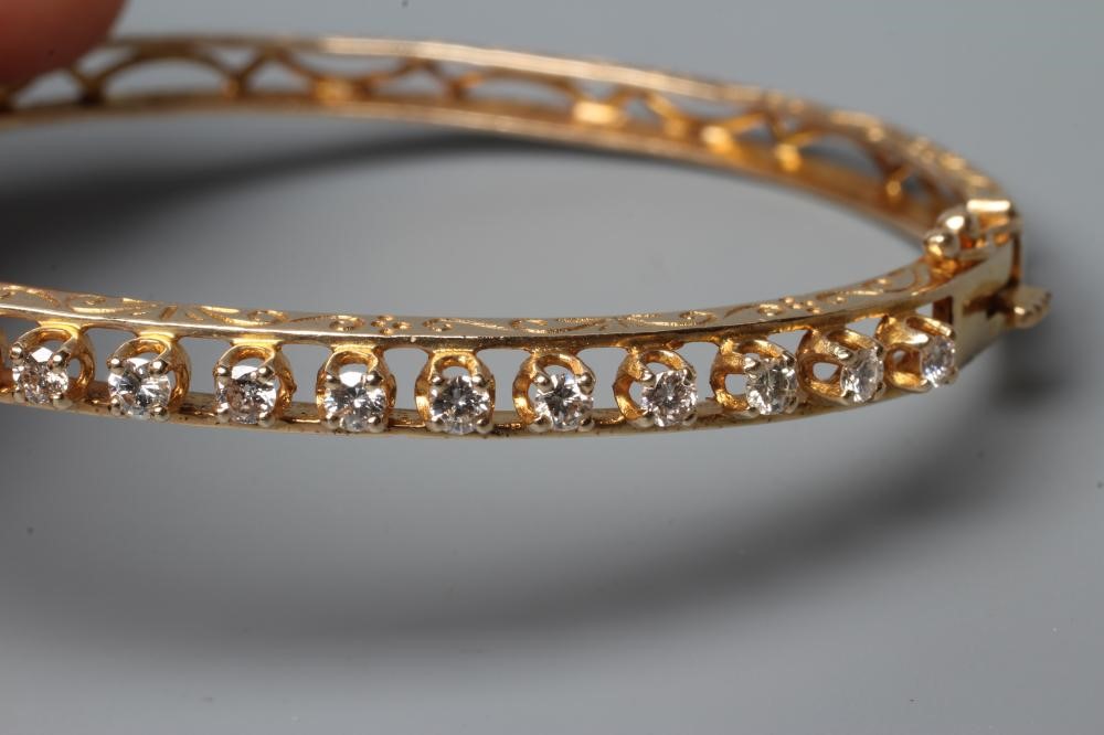 A DIAMOND SET STIFF HINGED BANGLE, the upper section claw set with seventeen small round brilliant Image