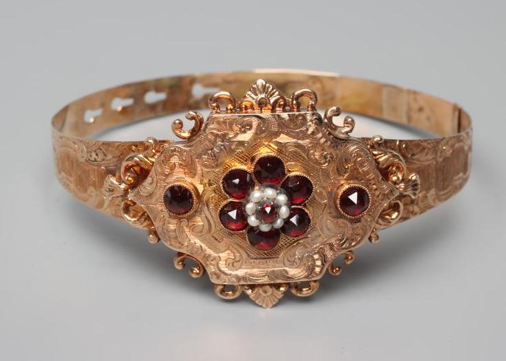 A MID 19TH CENTURY "BUCKLE" BANGLE, the upper section centred by a quatrefoil panel with garnet and Image