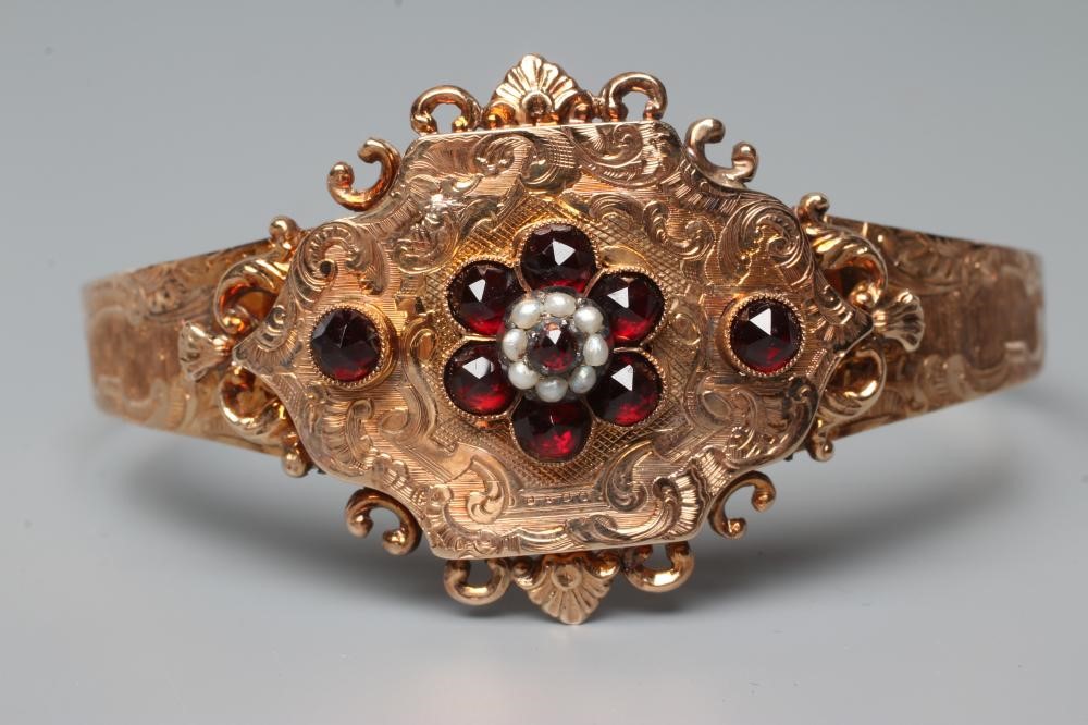 A MID 19TH CENTURY "BUCKLE" BANGLE, the upper section centred by a quatrefoil panel with garnet and Image