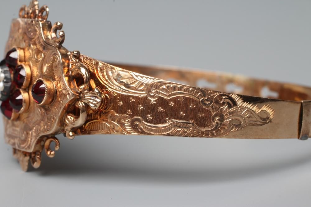 A MID 19TH CENTURY "BUCKLE" BANGLE, the upper section centred by a quatrefoil panel with garnet and Image
