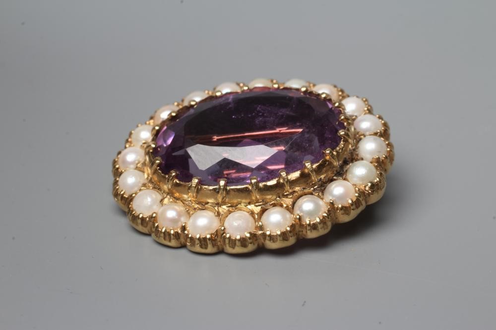 AN AMETHYST AND PEARL BROOCH, the oval facet cut amethyst claw set to a border of cultured pearls in Image