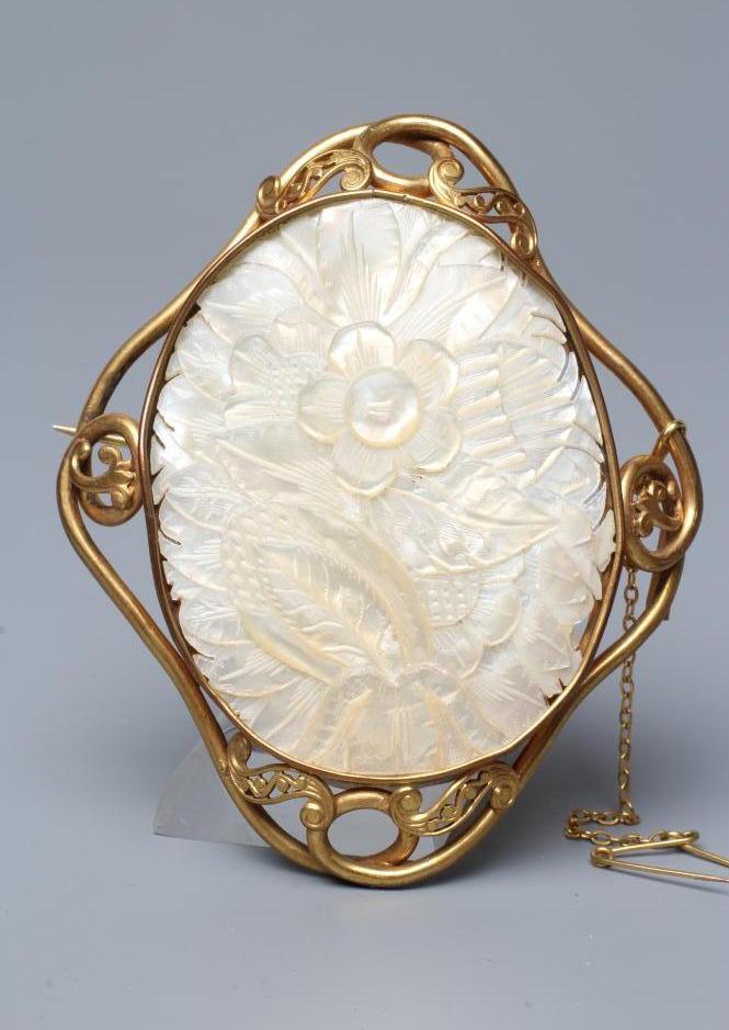 A CHINESE MOTHER OF PEARL OVAL PANEL carved with a flower and bud, collet set as a brooch in a Image
