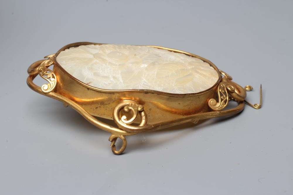 A CHINESE MOTHER OF PEARL OVAL PANEL carved with a flower and bud, collet set as a brooch in a Image