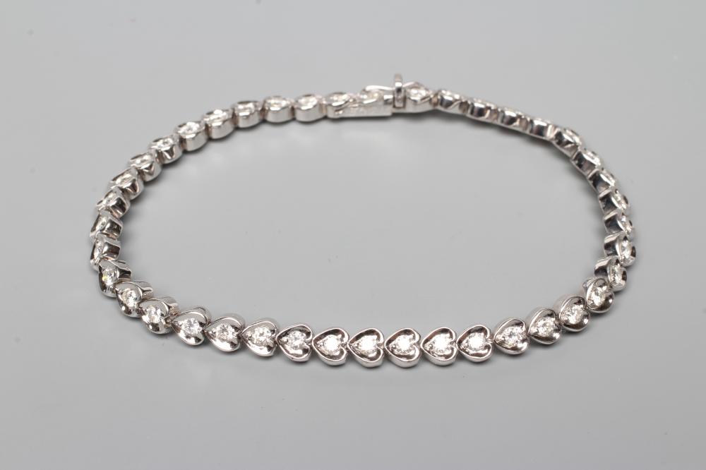 A DIAMOND TENNIS BRACELET, the forty one round brilliants in rub-over heart shaped links, clasp Image