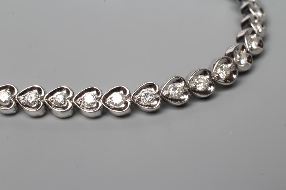 A DIAMOND TENNIS BRACELET, the forty one round brilliants in rub-over heart shaped links, clasp Image