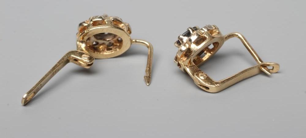 A PAIR OF SAPPHIRE AND DIAMOND CLUSTER EARRINGS, the oval facet cut sapphire claw set to a border of Image