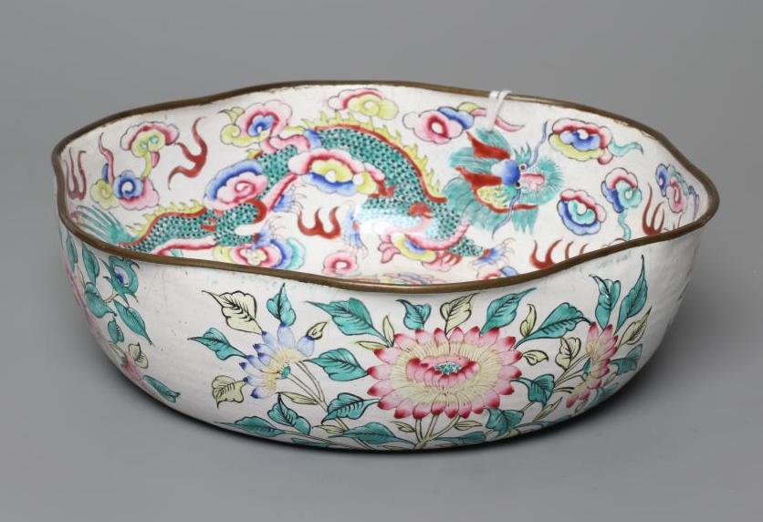 A CANTON ENAMEL BOWL of lobed circular form, painted in bright colours with dragons on a white Image