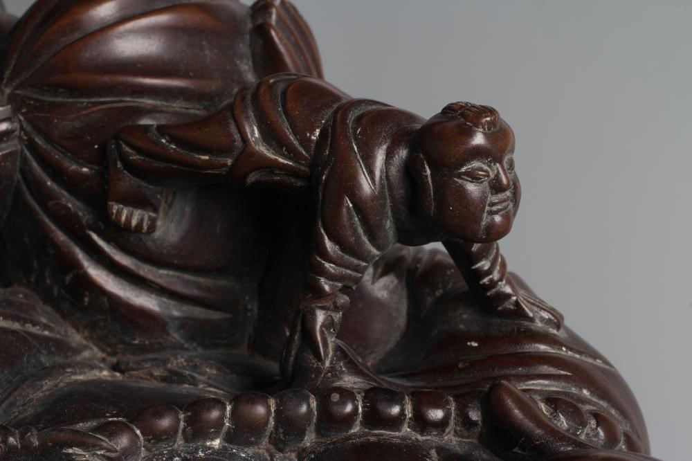 A CHINESE CARVED HARDWOOD BUDDAH, seated wearing a long bead necklace and with three children in Image