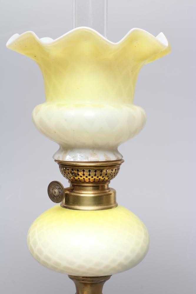 A SMALL VICTORIAN BRASS OIL LAMP, the yellow and white satin glass ball shaped shade and reservoir Image