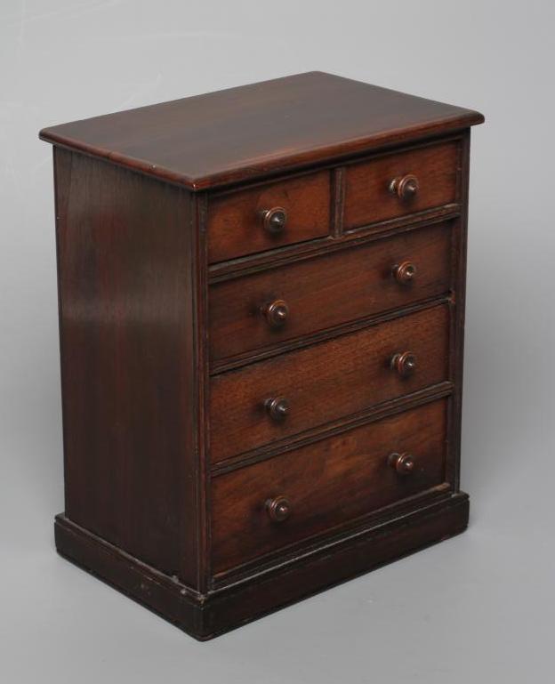 A MAHOGANY MINIATURE CHEST, early/mid 19th century, of two short over three long drawers with turned Image