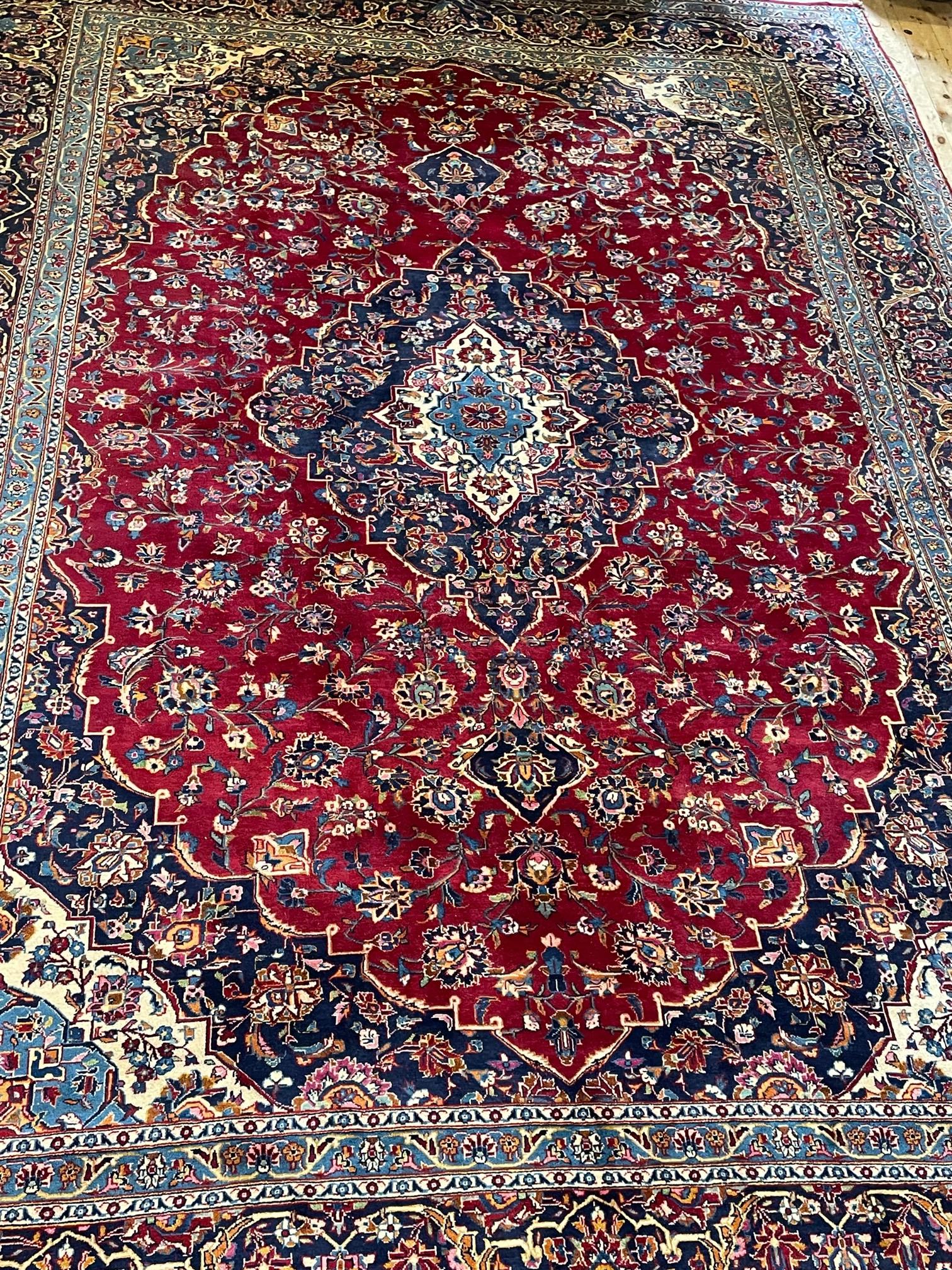 A KASHAN CARPET, the crimson floral field with central ivory and blue gul and spandrels within an Image