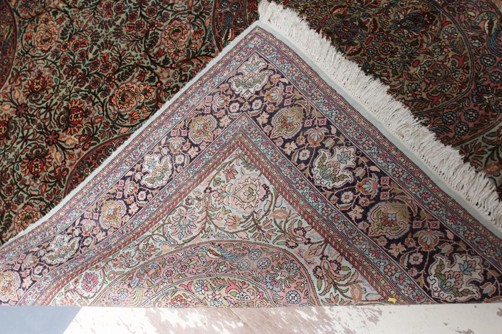 A PERSIAN SILK RUG, the pale green floral field with four oval guls with exotic birds, within an Image