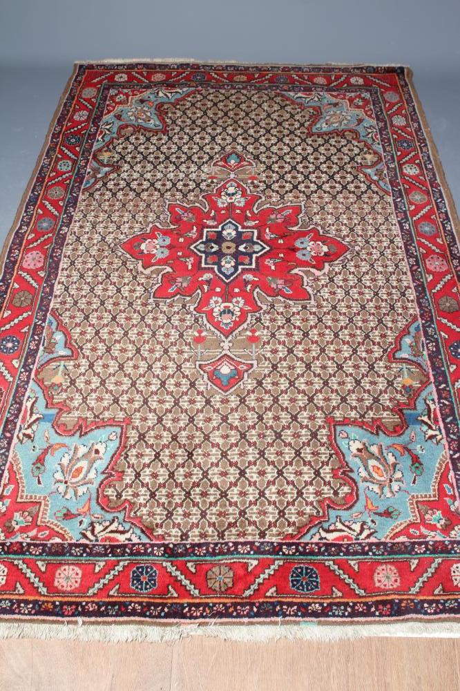 A PERSIAN RUG, the camel trellis patterned field with central crimson gul and pale blue spandrels, Image