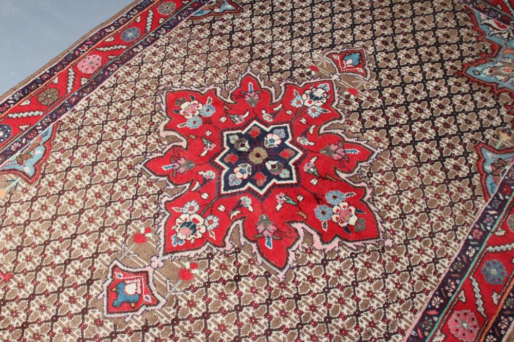 A PERSIAN RUG, the camel trellis patterned field with central crimson gul and pale blue spandrels, Image