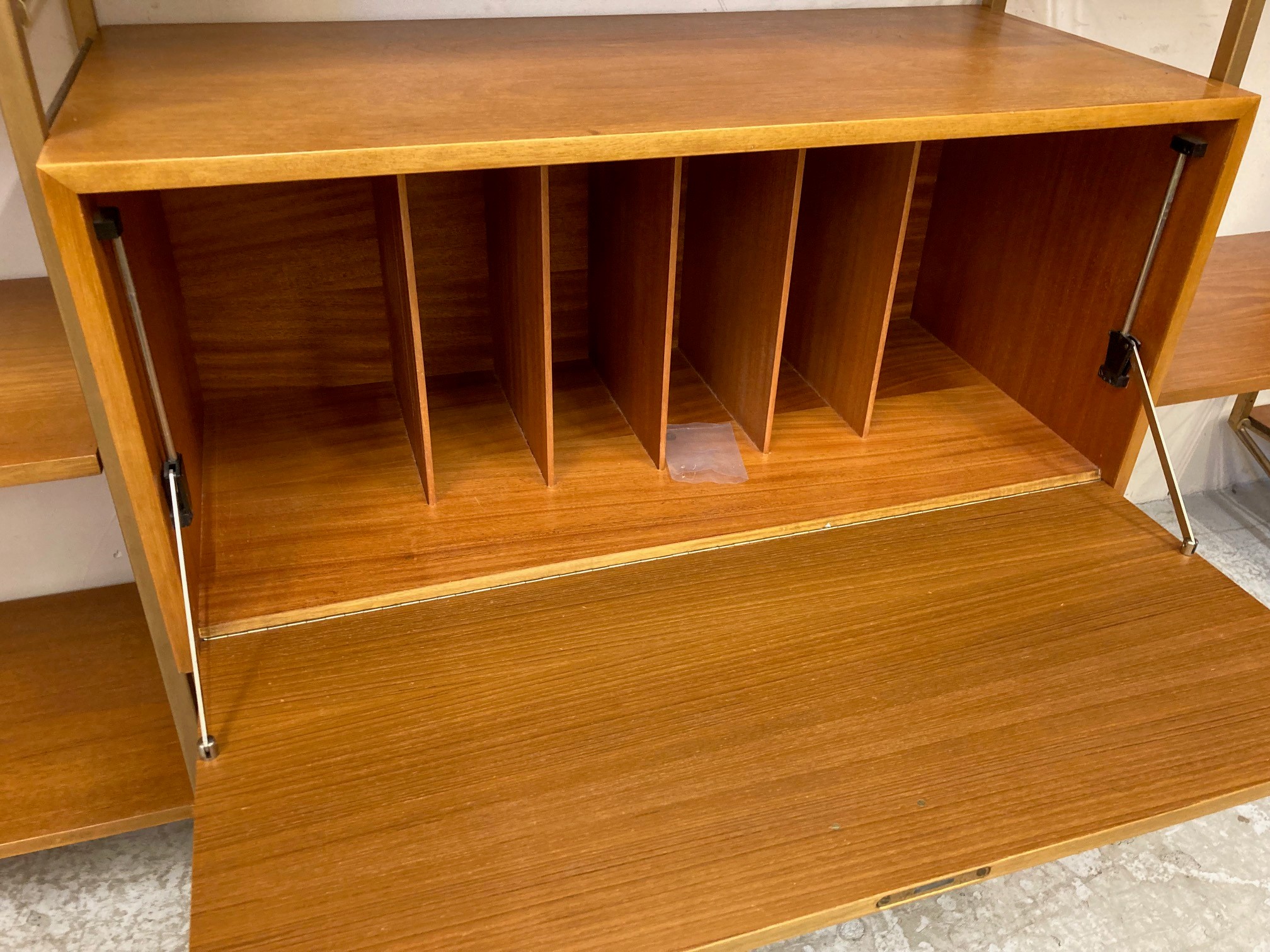 A TEAK STAPLES LADDERAX SECTIONAL MODULAR WALL UNIT in four sections raised on bronzed metal ladders Image