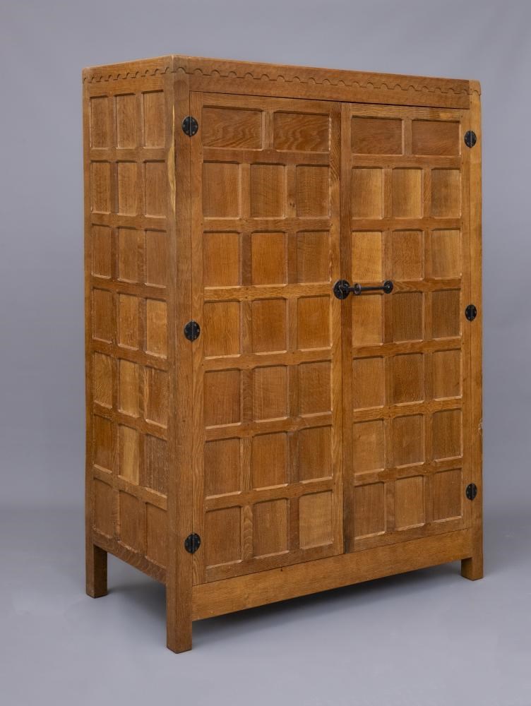 A ROBERT THOMPSON ADZED OAK WARDROBE of oblong multi panelled form with half penny moulded cornice Image
