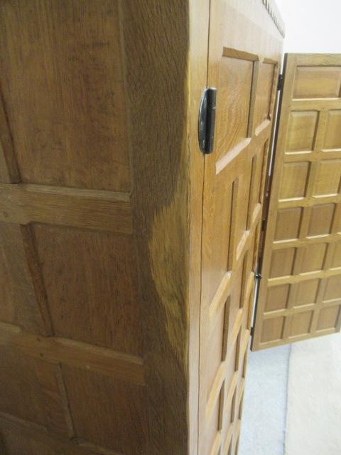 A ROBERT THOMPSON ADZED OAK WARDROBE of oblong multi panelled form with half penny moulded cornice Image
