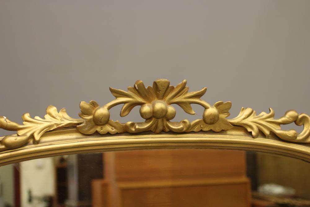 A VICTORIAN GILT WOOD PIER GLASS, the arched plate within a moulded frame with pierced and carved Image