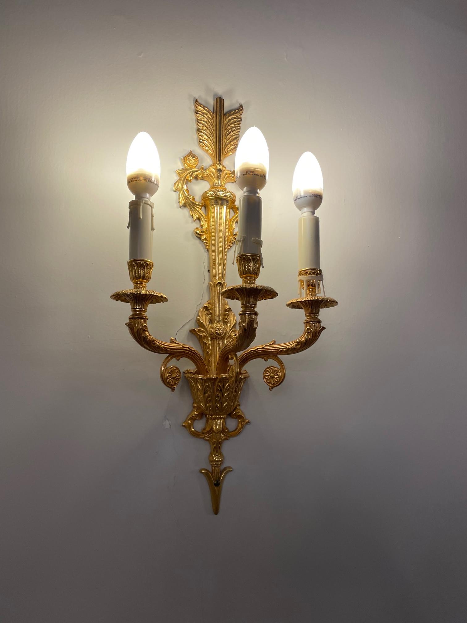 A SET OF FOUR GILT METAL THREE FLAME WALL LIGHTS Image