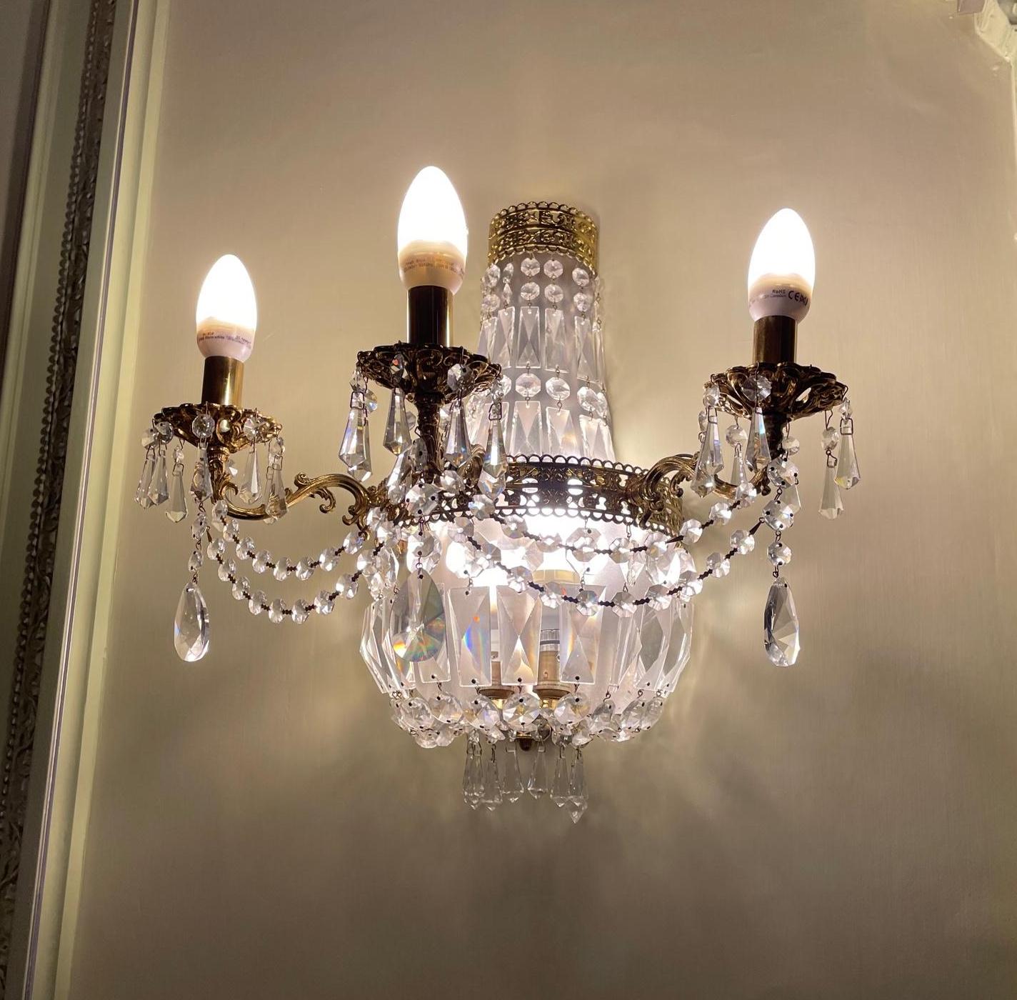 A SET OF FOUR GILT METAL AND CUT GLASS THREE FLAME WALL LIGHTS Image