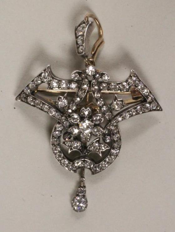 AN EDWARDIAN DIAMOND BROOCH/PENDANT of open cartouche form centred by a flowerhead cluster within an Image