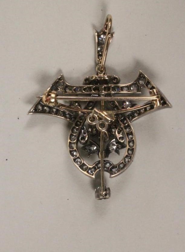 AN EDWARDIAN DIAMOND BROOCH/PENDANT of open cartouche form centred by a flowerhead cluster within an Image