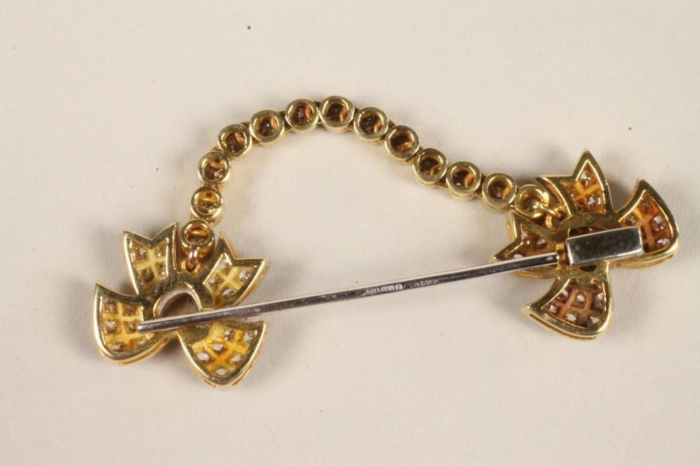 A DIAMOND "SWAG" BROOCH with two ribbon bows centred by a heart shaped stone and tied by a swag of Image