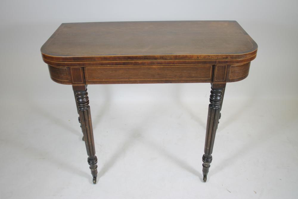 A REGENCY ROSEWOOD FOLDING CARD TABLE of rounded oblong form crossbanded with stringing Image