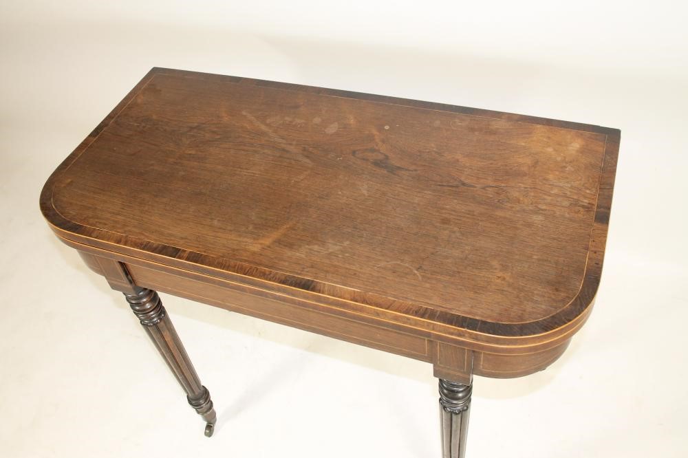A REGENCY ROSEWOOD FOLDING CARD TABLE of rounded oblong form crossbanded with stringing Image